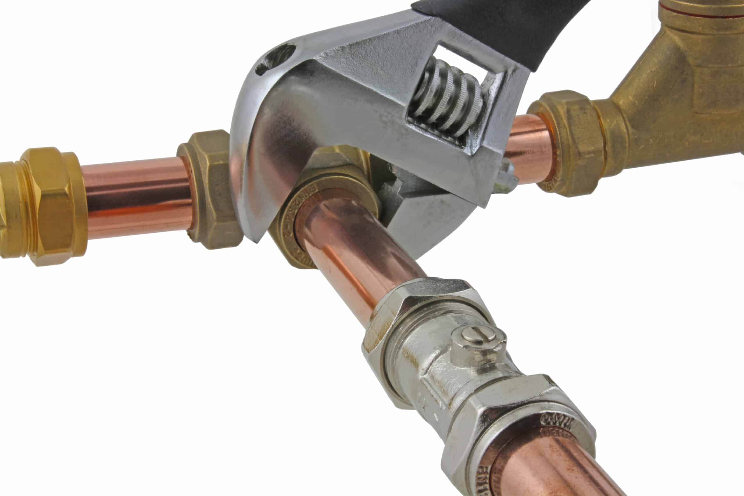 An adjustable wrench tightening a compression fitting to copper pipework during repiping.